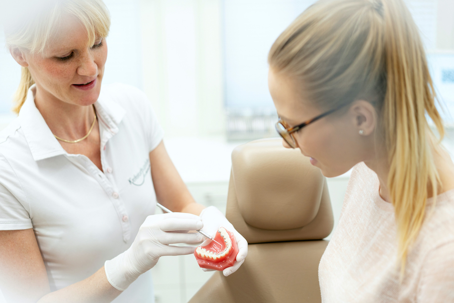 Kieferorthopädin erklärt einer Patientin anhand eines Zahnmodells den Behandlungsablauf.
