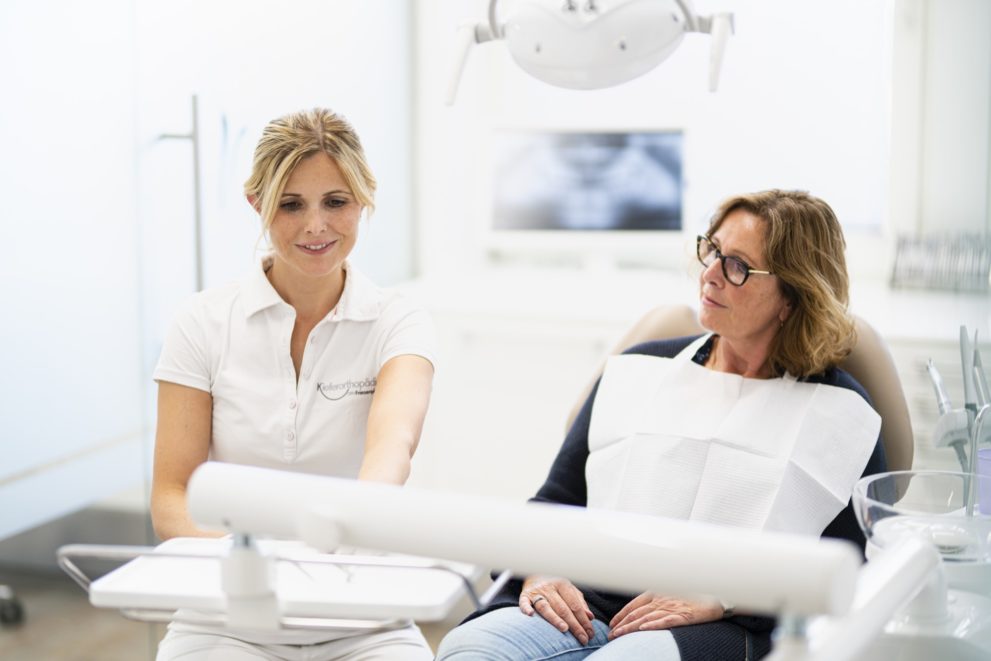 Kieferorthopädin bespricht mit einer Patientin im Behandlungszimmer die Ergebnisse.